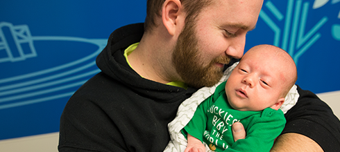 Jackson, spina bifida patient, being held by his father
